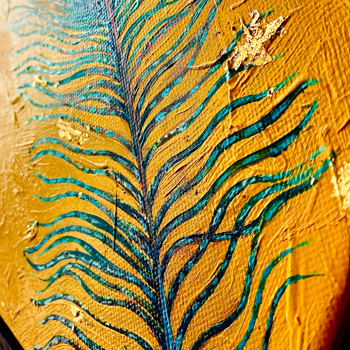 Close-up of a peacock feather with gold and blue details on a textured surface.