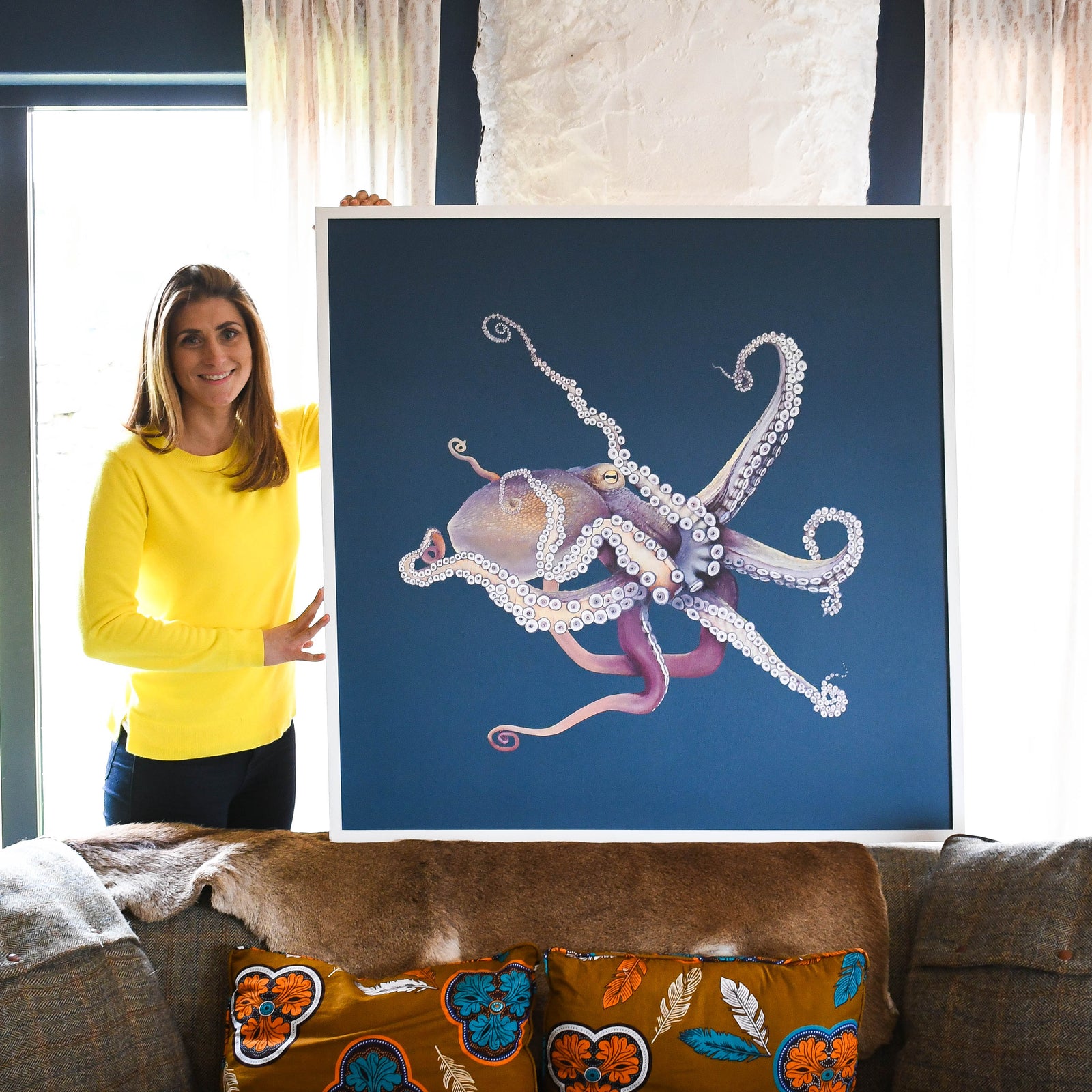 Woman standing next to a large painting of an octopus in a living room.