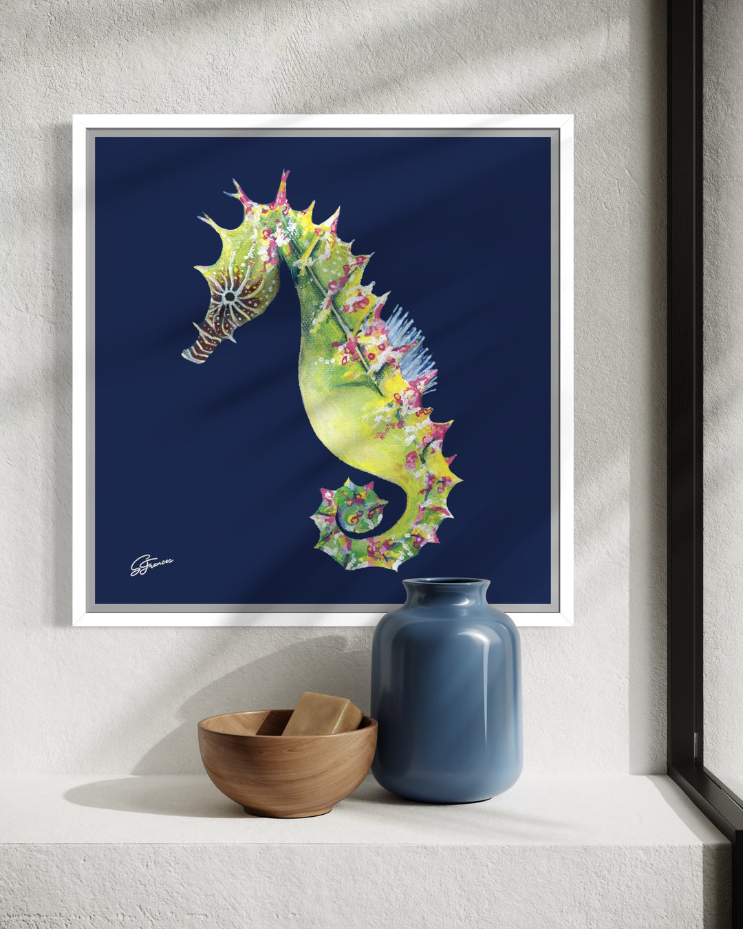 Framed artwork of a colorful seahorse on a wall with decorative items below.