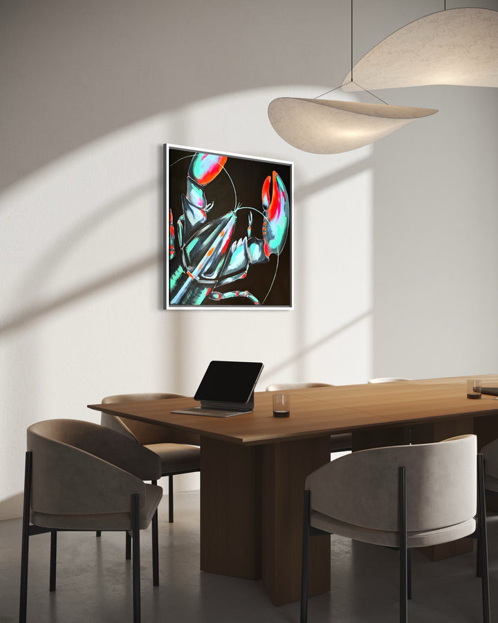 A framed abstract art print with vibrant teal, red, and black brushstrokes hangs on a light gray wall in a modern dining room setting with a wooden table, gray chairs, and a pendant light.
