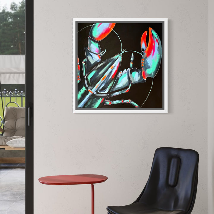 A framed abstract lobster painting with vibrant green, red, and orange tones on a black background, displayed on a light gray wall above a black chair and a small red side table.