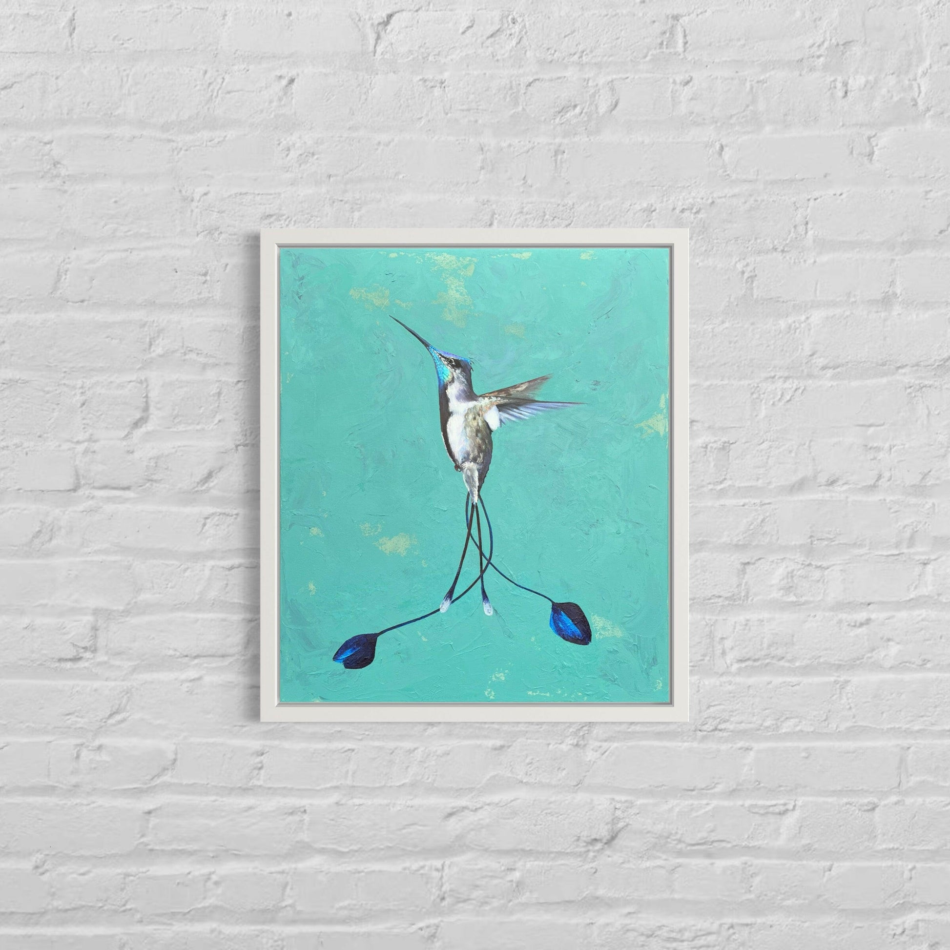 humming bird painting on a dusty green hue canvas , in a white frame on a white brick wall