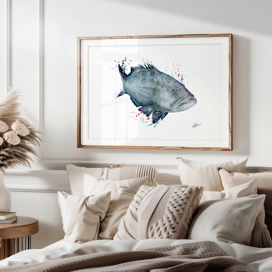 Framed artwork of a fish on a wall above a bed with pillows and blankets.