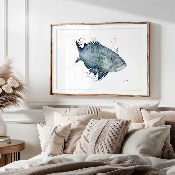 Framed artwork of a fish on a wall above a bed with pillows and blankets.